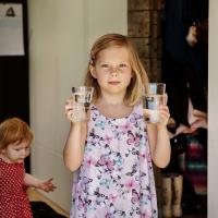 Pige med to vandglas i hænderne